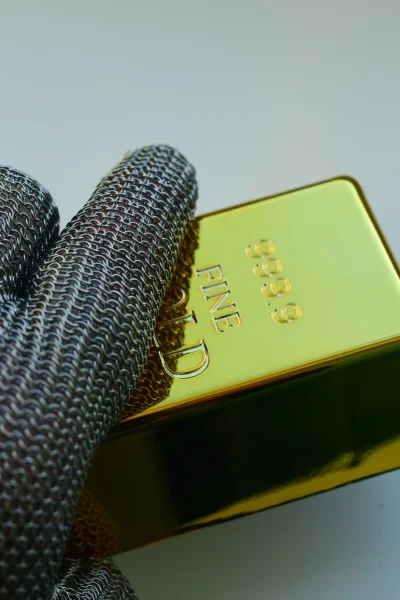 Hand met handschoen die een fijngoudbaar vasthoudt